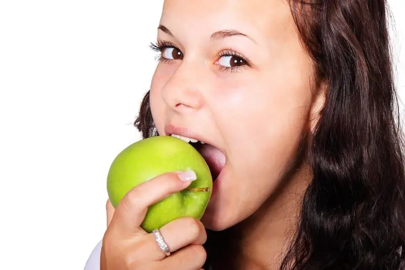 Young girl biting into a green apple