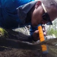 Man drinking water through a purifying water straw