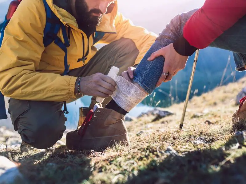 Man bandaging someone's leg outdoors