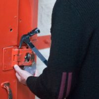Man opening red door with a sledgehammer