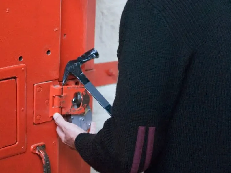 Man opening red door with a sledgehammer