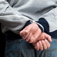 a man's hands zip tied behind his back