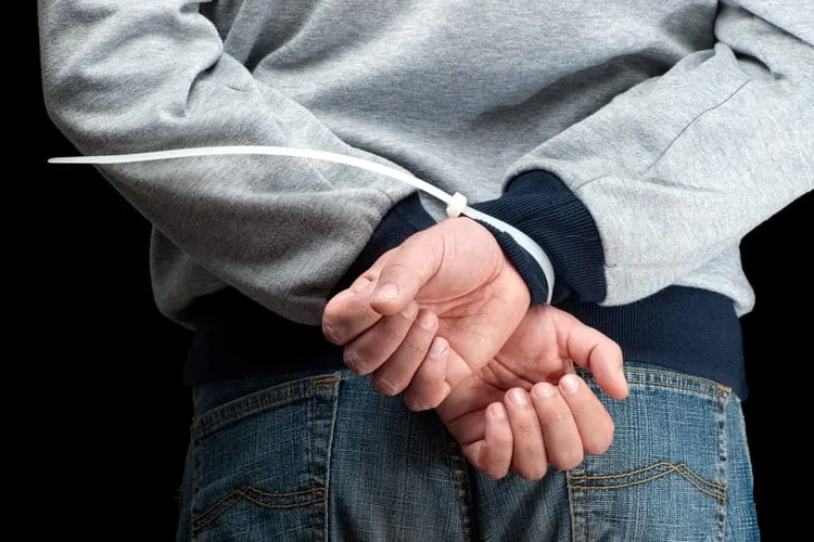 a man's hands zip tied behind his back