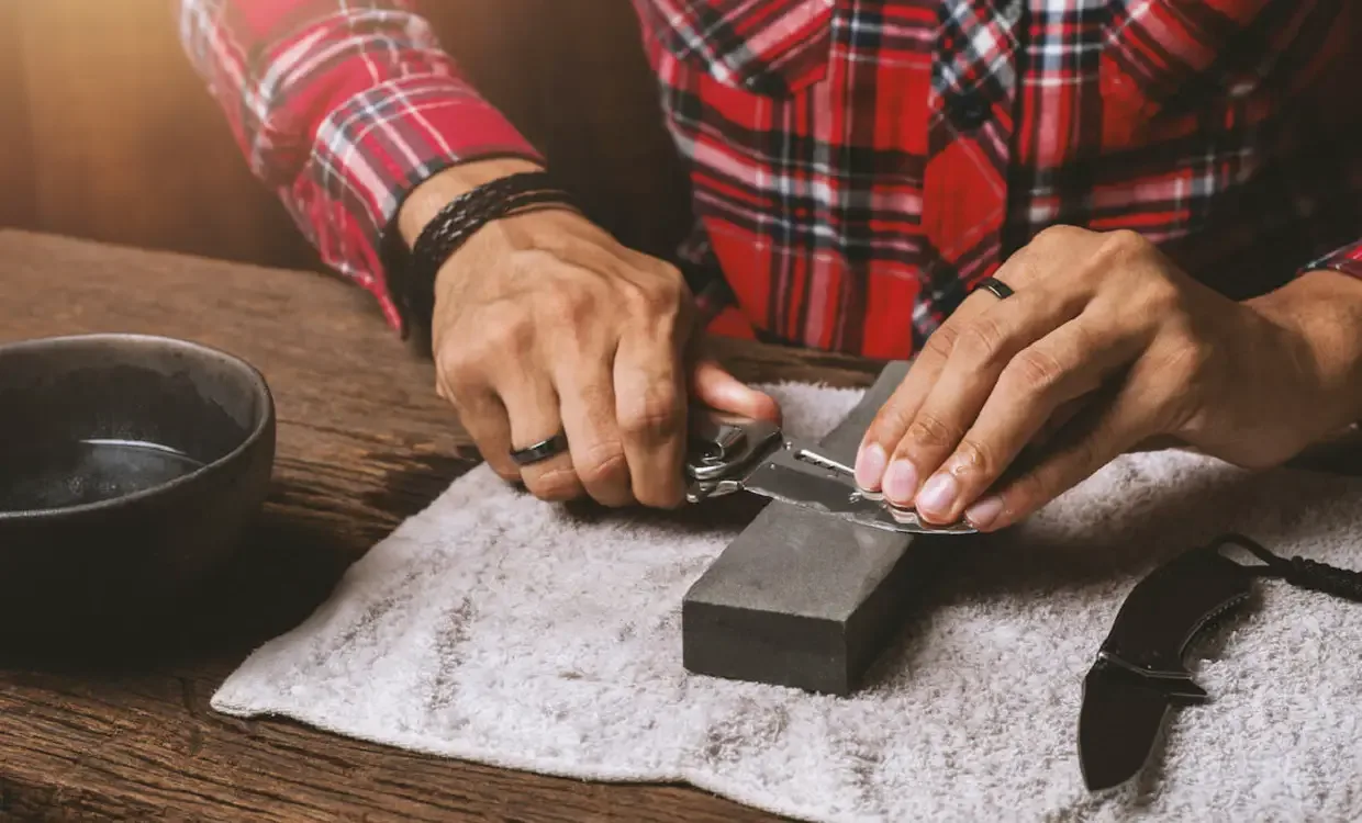 Man sharpening pocket knife on a sharpening stone