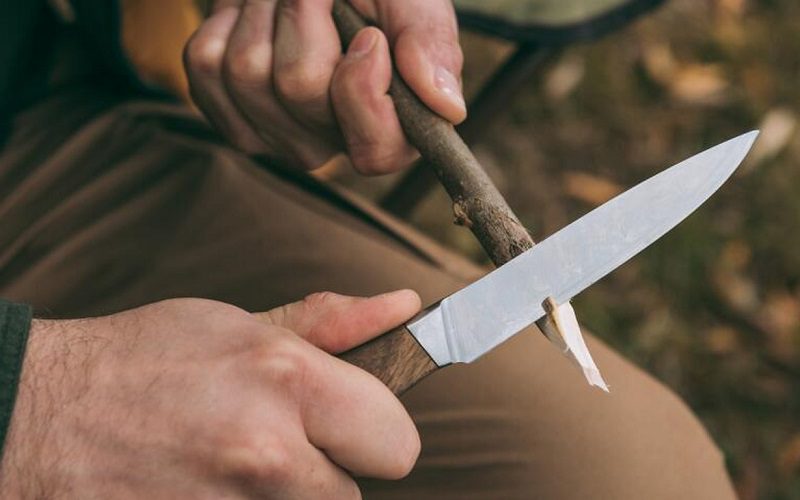 12 Essential Camping Skills for Outdoor Survival 9 using a knife on a wood